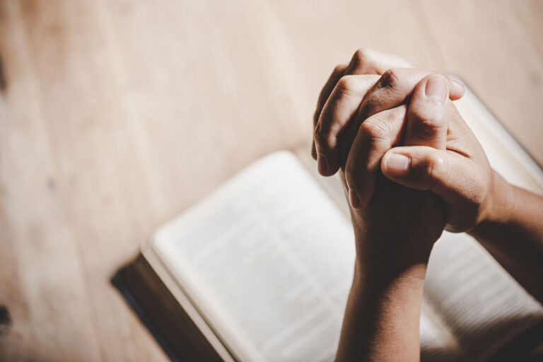 religion-and-divorce Hands Praying over a religious Book